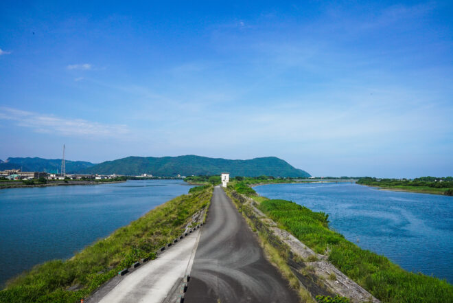 青空と川沿いに続く一本道の風景